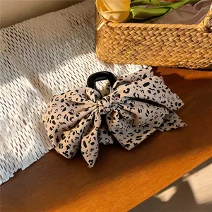 Detalle de una pinza para el pelo vintage con lazo de tela de leopardo en fondo rústico.