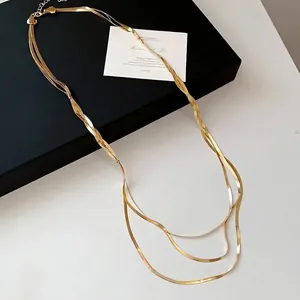 Minimalistische dreilagige goldene Schlangenkette auf einer schwarzen Geschenkbox