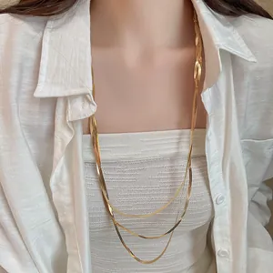 Detailansicht einer eleganten dreilagigen goldenen Schlangenkette für Damen auf weißem Hemd