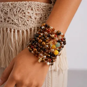 Detailed macro view of a bohemian multilayer bracelet with tiger eye beads and charms.