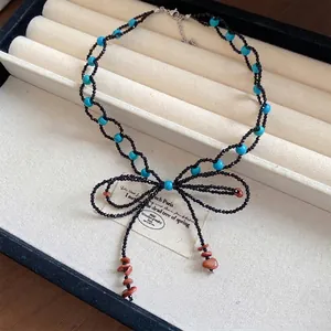 Squisita collana fatta a mano con perle e fiocco, accenti turchesi e dettagli di frange eleganti