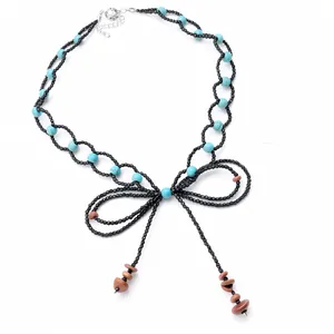 Collana di perline fatta a mano con fiocco e nappe in pietra su sfondo bianco pulito