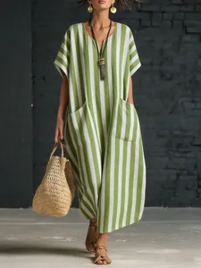 Detail view of a loose green and white striped V-neck maxi dress with front pockets