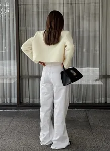 Rückansicht einer schicken französischen Tweed-Kurzjacke in Creme mit weißer Hose.