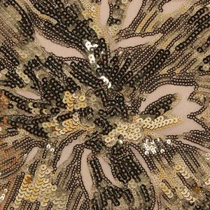 Primo piano dettagliato di intricati motivi di paillettes oro e nere su rete trasparente
