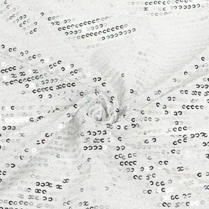 Close-up macro detail of white shimmering sequins on elegant cocktail dress fabric