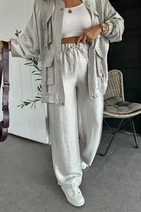 Dettaglio del tessuto in raso argento lucido di questo set di giacca e pantaloni cargo.