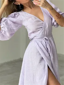 Close-up of a lilac linen wrap dress with puff sleeves and tie waist detail