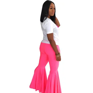 Vista lateral de una mujer con pantalones de campana rosa neón y una camiseta blanca básica
