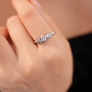 Macro detail of a silver-tone ring with multiple round zircons on a model's finger.