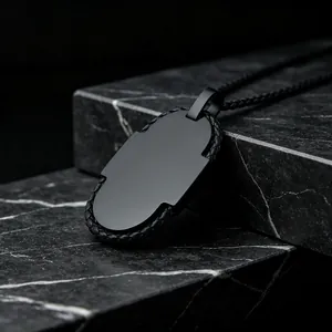 Κοντινή όψη οβάλ μενταγιόν dog tag σε μαύρο ματ χρώμα με πλεκτή μπορντούρα σε μάρμαρο.
