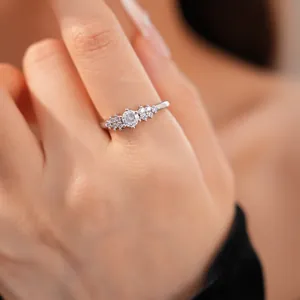 Close-up of an exquisite silver-colored ring with a round zircon stone on a finger.