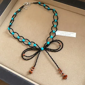 Dettaglio della collana a fiocco di perline con accenti turchesi e nappe in pietra.