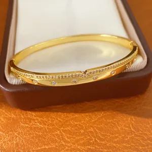 Gros plan détaillé d'un bracelet jonc plaqué or 18 carats avec des zircons étincelants.