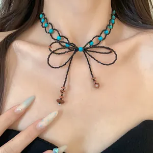 Vista dettagliata di una collana di perline fatta a mano con fiocco e accenti turchesi.