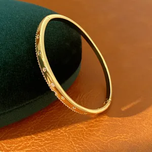 Détail d'un jonc plaqué or 18K avec zircons scintillants sur fond en cuir texturé
