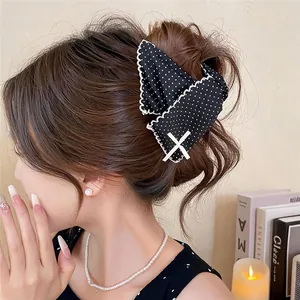 Elegant black polka dot bow hair claw clip with lace trim shown on an Asian model.