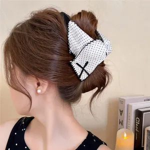 Elegant white polka dot bow hair claw clip shown in a stylish updo hairstyle