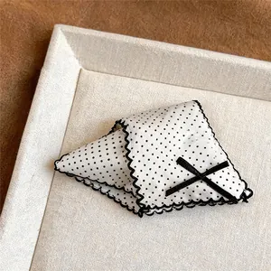 Detailed view of an elegant white polka dot hair claw clip with black lace edges