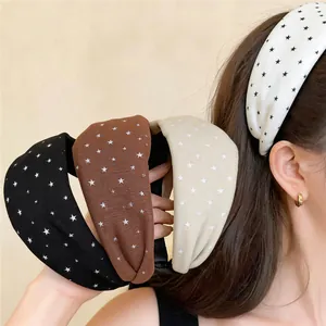 Detail of wide fabric headbands with star patterns in black, brown, beige, and white.