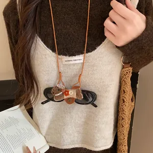 Détail d'un collier pince à lunettes fait main avec un chiot floqué et des perles.