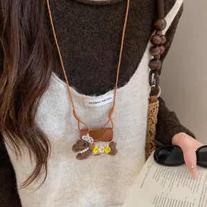 Gros plan d'un collier porte-lunettes chiot en peluche avec cordon cuir et perles.
