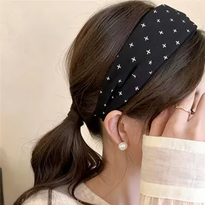 Close-up view of elegant black fabric wide headband with white star pattern on model