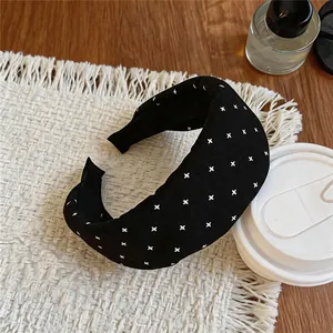 Detailed view of black fabric wide-brimmed headband with white pattern on a mat