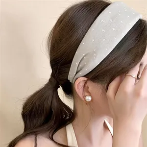 Close-up of model wearing a grey printed fabric wide headband and pearl earrings.