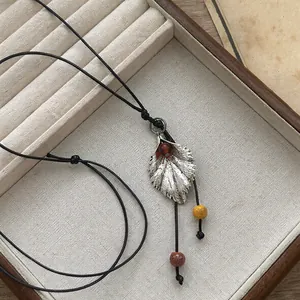 Primer plano de collar con colgante de hoja de plata vintage y cuentas de colores