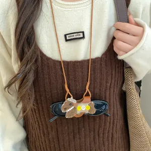 Gros plan d'un collier porte-lunettes chiot bohème avec cordon en cuir et détails floqués.