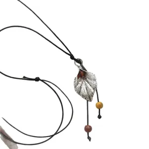 Collar artístico con colgante de hoja, cuentas de cerámica y cordón de cuero negro
