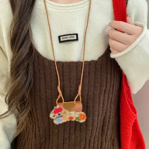 Détail d'un collier pince à lunettes chiot floqué porté sur une tenue en maille décontractée