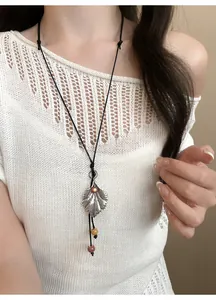 Vista detallada del collar con colgante de hoja y cuentas en modelo con top de ganchillo