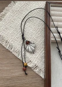 Detalle del collar con colgante de hoja vintage con piedra de resina y cordón de cuero.