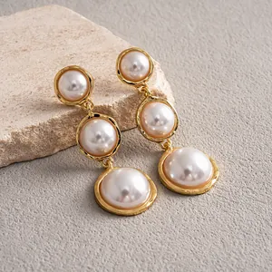 Close-up detail of vintage gold-plated drop earrings with graduated round pearls