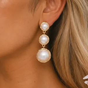 Detailed view of elegant vintage gold-tone tiered pearl stud earrings on a model