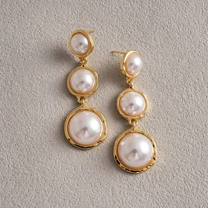 Macro detail of vintage gold-tone earrings with triple cascading round pearls