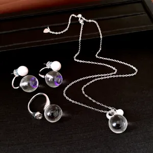 Detailansicht eines luxuriösen Schmucksets aus Harz und Zirkon mit weißen Perlen auf schwarzem Stoff.