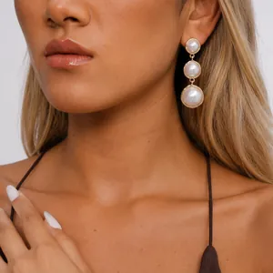 Detailed close-up showing vintage gold pearl drop earrings with three round pearls on a model