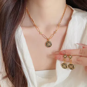 Detail eines vintage 24K vergoldeten Halsketten- und Ohrring-Sets mit Emaille-Blumen.