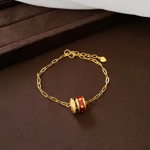 Nahaufnahme eines 24K vergoldeten Armbands mit rot-schwarzem Emaille-Anhänger.