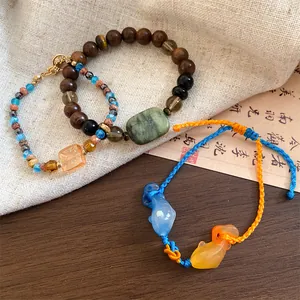 Gedetailleerd overzicht van armbanden in nieuwe Chinese stijl met houten kralen en koi bedels.