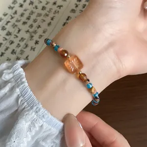 Detailopname van een kralenarmband in nieuwe Chinese stijl met een oranje bloemenbedel