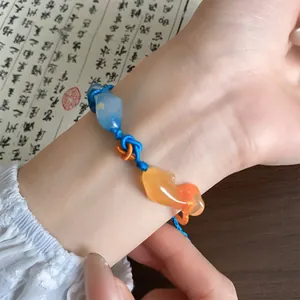 Prachtige geweven armband in Chinese stijl met koivishangers aan een pols gedragen