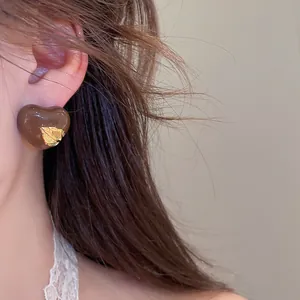 Nahaufnahme eines Vintage-Ohrsteckers in Herzform mit Blattgold-Detail am Ohr getragen