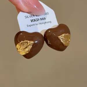 Nahaufnahme von Maillard braunen Emaille-Herzohrringen mit 18K vergoldetem Blatt.