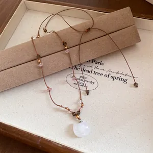 Gros plan d'un collier rétro style Maillard avec pendentif chat blanc et cordon en cuir.