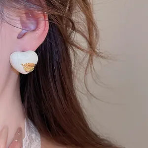 Detailansicht eines 18k vergoldeten Herzohrrings aus Emaille mit Goldblattdekor