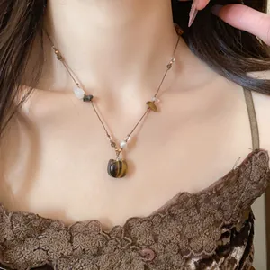 Gros plan d'un collier de perles en pierre de style Maillard avec un joli pendentif chaton
